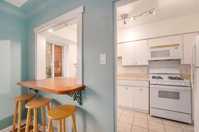 665 Washington St Unit 5B, Denver, CO 80203 - kitchen with white appliances, white cabinetry, light tile patterned floors, light countertops, and a breakfast bar