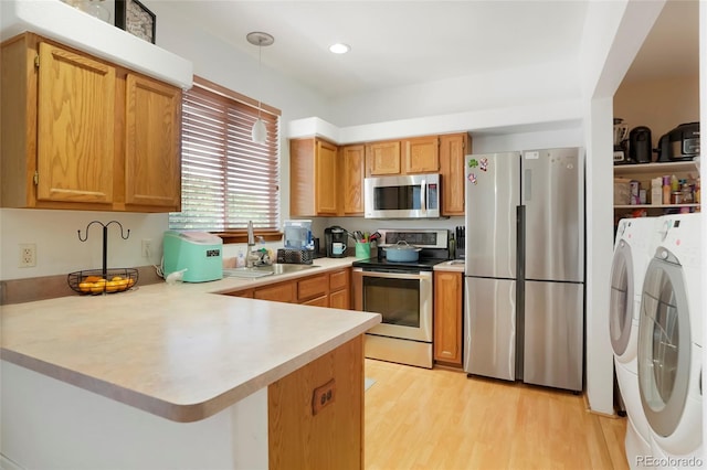 7520 W Coal Mine Ave Unit C, Littleton, CO 80123 - kitchen with appliances with stainless steel finishes, washer and clothes dryer, a peninsula, light countertops, and light wood-type flooring