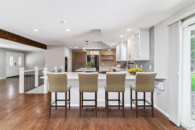 6330 E Vassar Ave, Denver, CO 80222 - kitchen with island range hood, stainless steel fridge, backsplash, a peninsula, and white cabinetry