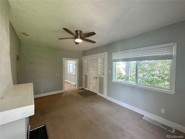 interior space featuring visible vents, baseboards, dark carpet, a closet, and a textured ceiling