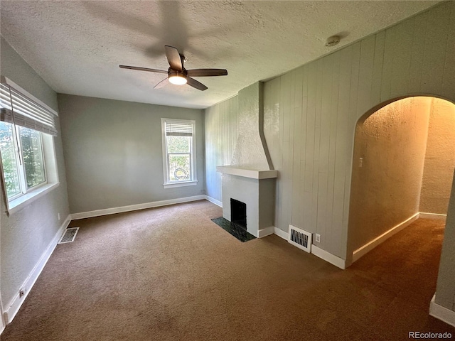 unfurnished living room with visible vents, a fireplace, ceiling fan, a textured ceiling, and carpet flooring