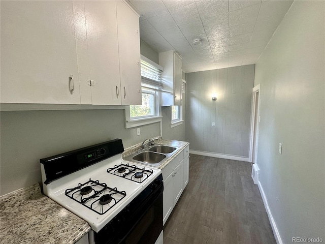 kitchen with gas stove, dark wood-style floors, white cabinets, and a sink