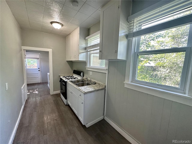 kitchen featuring range with gas stovetop, dark wood-style flooring, a sink, light countertops, and white cabinets