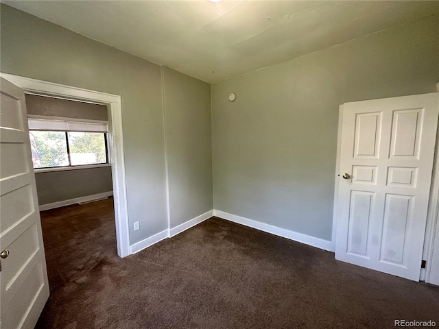 interior space with dark carpet and baseboards