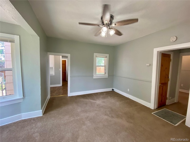 unfurnished room with visible vents, baseboards, carpet, and a ceiling fan