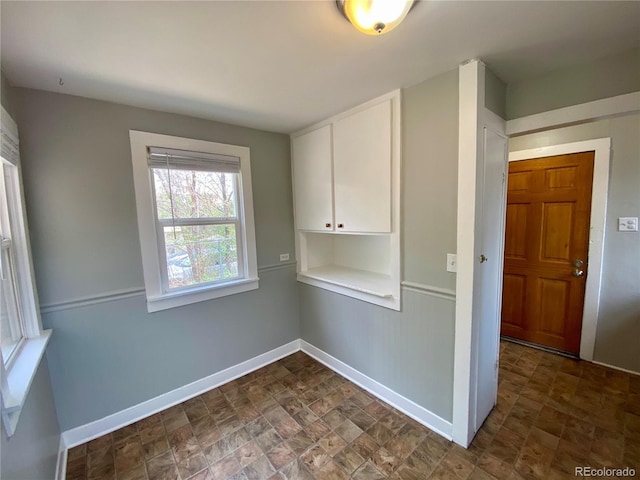 empty room with baseboards and stone finish floor