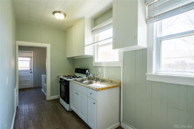 kitchen featuring a sink, dark wood-style flooring, light countertops, white cabinetry, and gas range oven