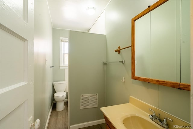 bathroom with visible vents, baseboards, toilet, vanity, and wood finished floors