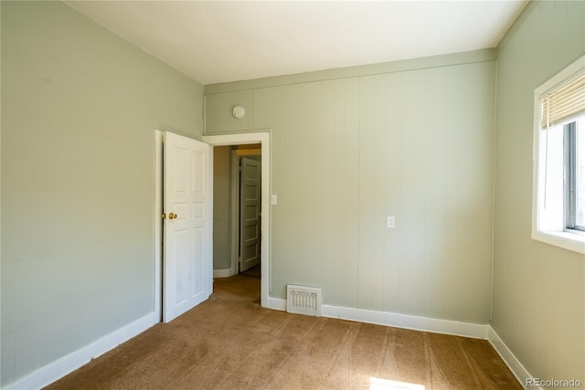 carpeted spare room with visible vents and baseboards