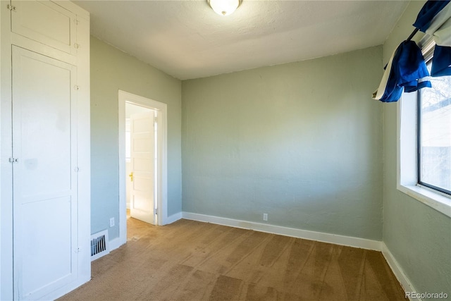 unfurnished bedroom with light colored carpet, baseboards, and visible vents