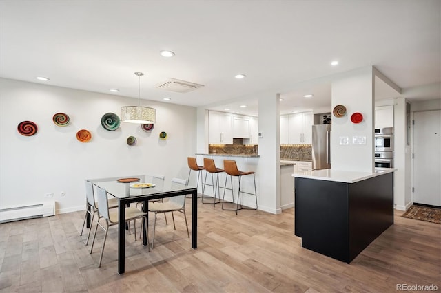 interior space featuring light wood-type flooring, white cabinets, decorative backsplash, appliances with stainless steel finishes, and decorative light fixtures