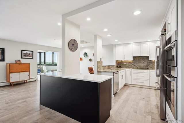 kitchen featuring white cabinetry, backsplash, kitchen peninsula, light hardwood / wood-style flooring, and stainless steel dishwasher