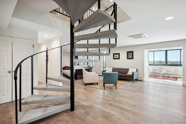 stairway with hardwood / wood-style floors and a baseboard radiator