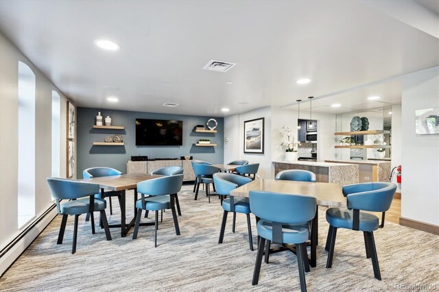 dining area with indoor bar, light hardwood / wood-style floors, and baseboard heating