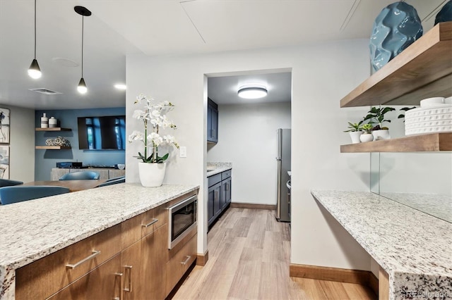 3131 E Alameda Ave Unit 1107, Denver, CO 80209 - kitchen featuring appliances with stainless steel finishes, open shelves, light wood finished floors, pendant lighting, and light stone countertops