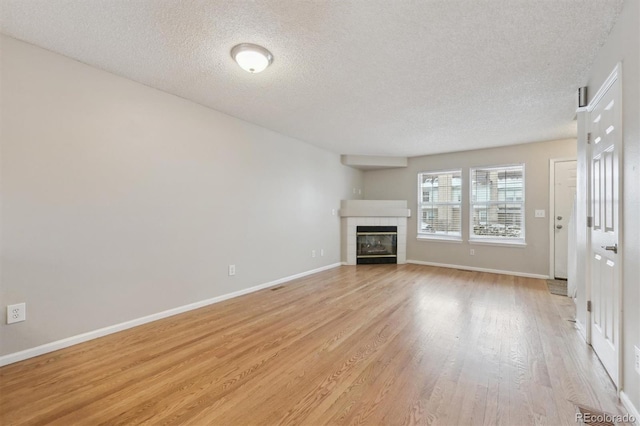 unfurnished living room with a fireplace, a textured ceiling, and light hardwood / wood-style flooring