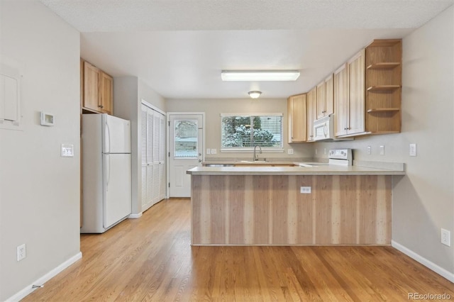 kitchen with kitchen peninsula, light brown cabinets, white appliances, and sink