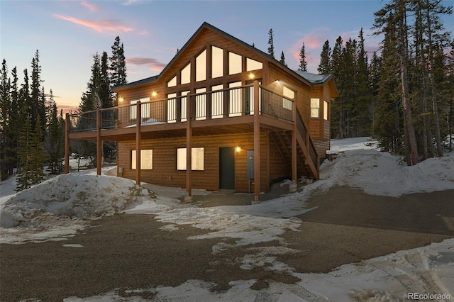 snow covered back of property with a wooden deck