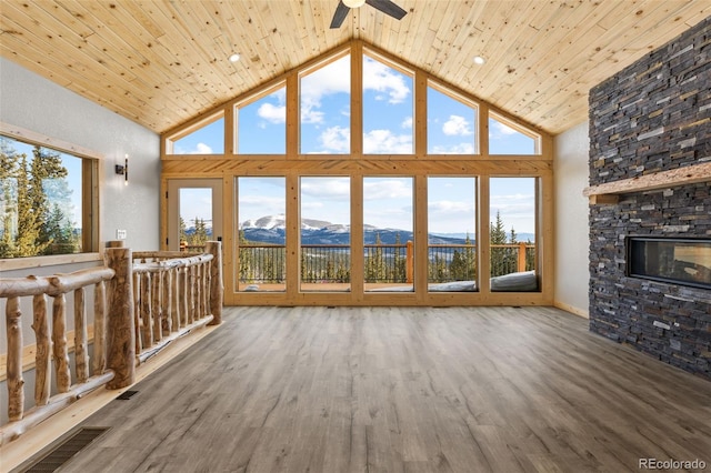 unfurnished living room featuring hardwood / wood-style flooring, high vaulted ceiling, a fireplace, a mountain view, and wooden ceiling