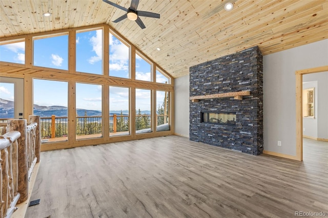 unfurnished living room featuring high vaulted ceiling, a fireplace, wood-type flooring, a mountain view, and wooden ceiling