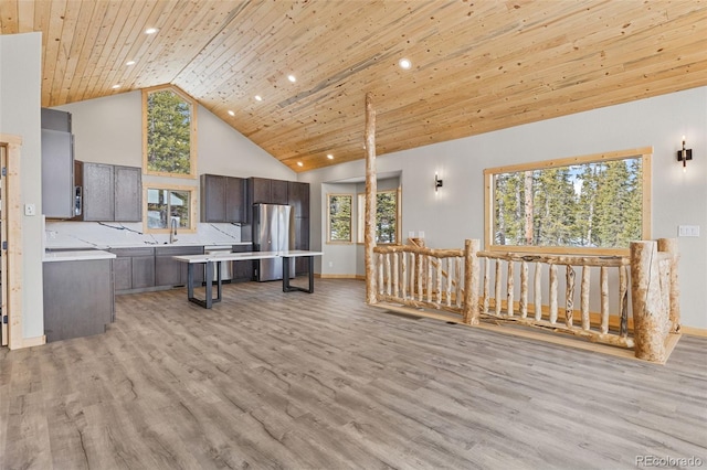 kitchen featuring wood ceiling, stainless steel refrigerator, high vaulted ceiling, dark brown cabinetry, and light wood-type flooring