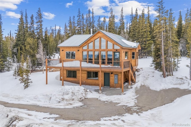 snow covered rear of property featuring a deck