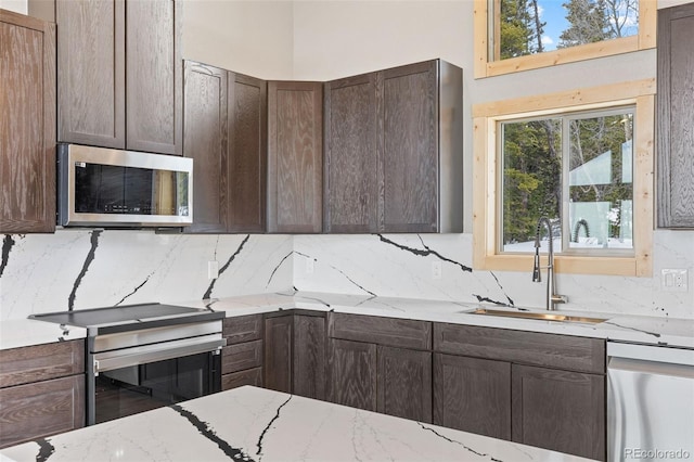 kitchen featuring stainless steel appliances, sink, light stone counters, and decorative backsplash