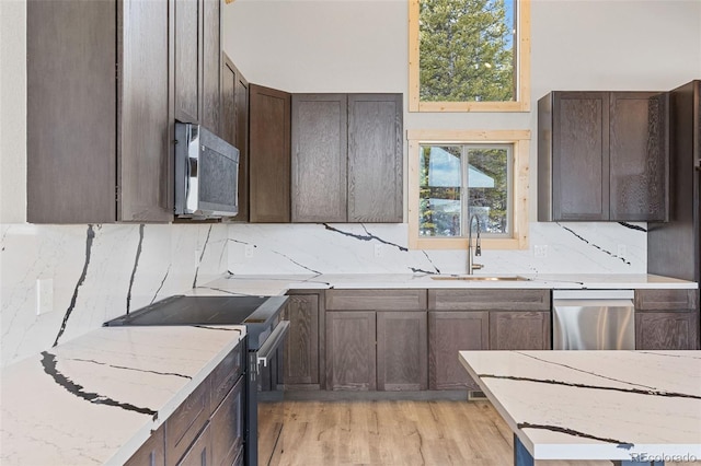 kitchen featuring dark brown cabinetry, sink, light stone counters, tasteful backsplash, and stainless steel appliances