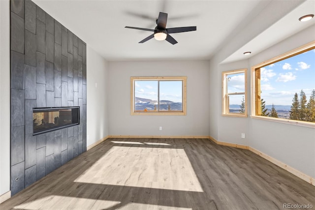 unfurnished living room with ceiling fan, a fireplace, and dark hardwood / wood-style flooring