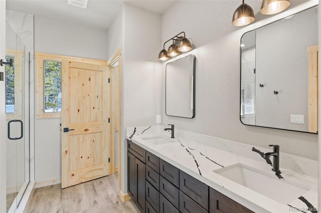 bathroom with hardwood / wood-style flooring, vanity, and an enclosed shower