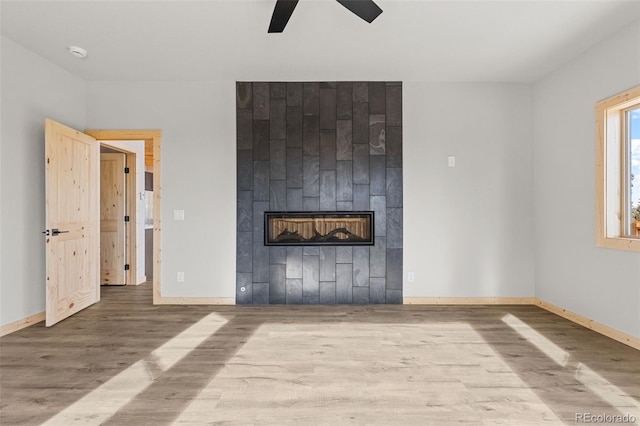 unfurnished living room featuring hardwood / wood-style flooring, a tile fireplace, and ceiling fan