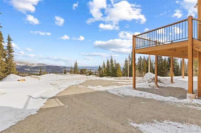 snowy yard featuring a deck with mountain view