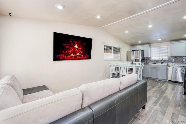 living room featuring lofted ceiling, sink, and light wood-type flooring