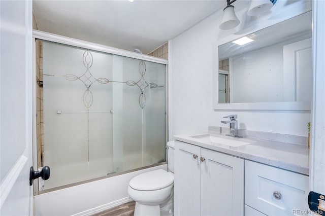 full bathroom featuring enclosed tub / shower combo, vanity, and toilet