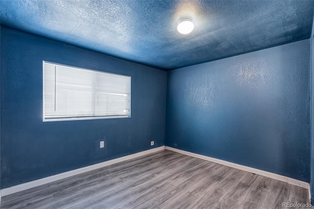 spare room featuring hardwood / wood-style floors and a textured ceiling