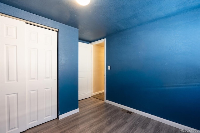 unfurnished bedroom featuring dark hardwood / wood-style flooring, a closet, and a textured ceiling