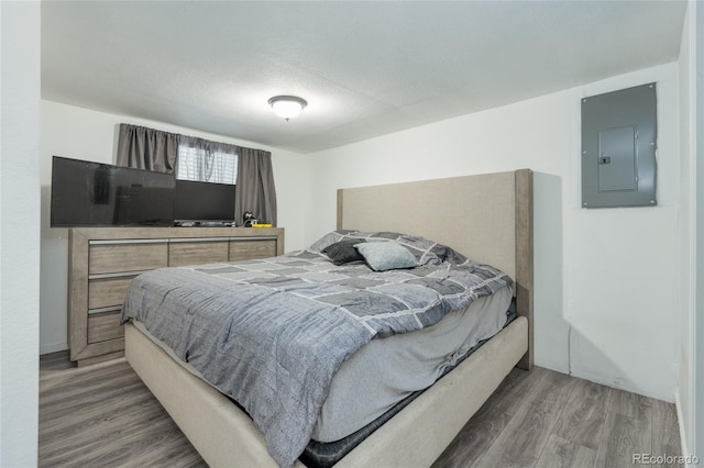 bedroom with a textured ceiling, electric panel, and dark hardwood / wood-style flooring