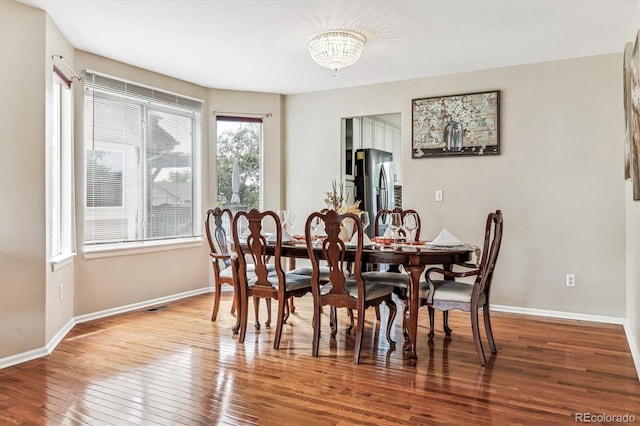 dining area with plenty of natural light, hardwood / wood-style floors, and a chandelier