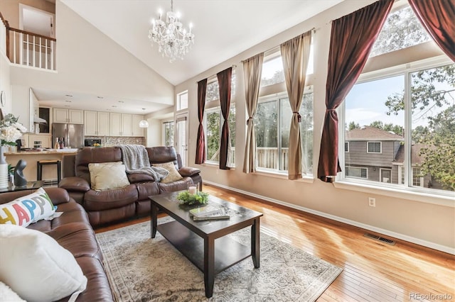 living room with light hardwood / wood-style flooring, an inviting chandelier, and high vaulted ceiling