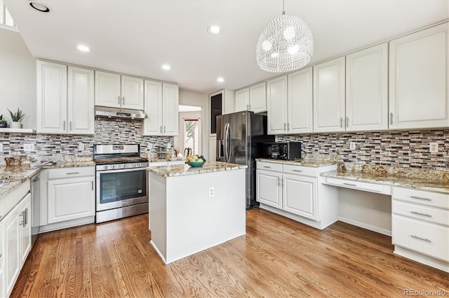 kitchen featuring white cabinets, pendant lighting, stainless steel appliances, and light hardwood / wood-style floors