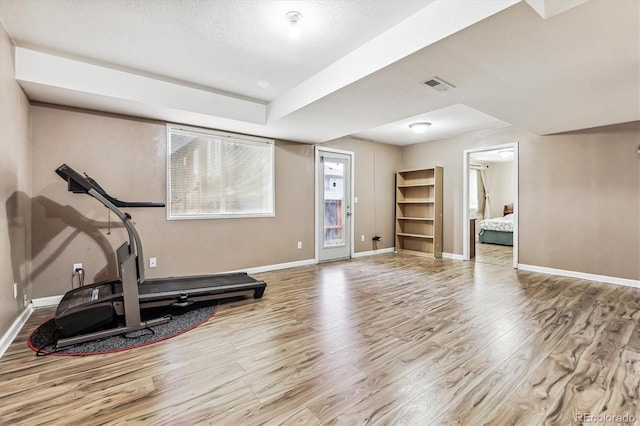 workout area with a textured ceiling and light wood-type flooring