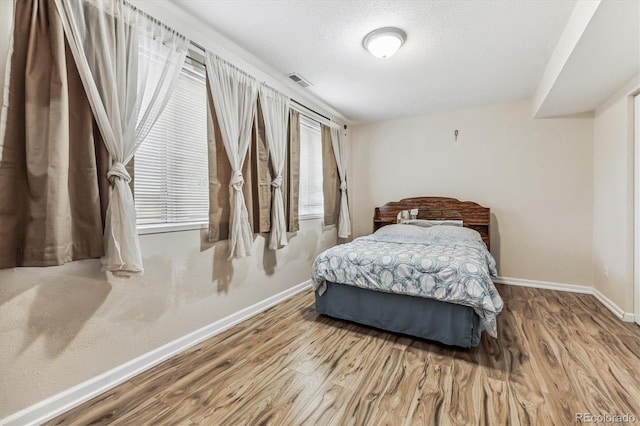 bedroom with a textured ceiling and hardwood / wood-style flooring