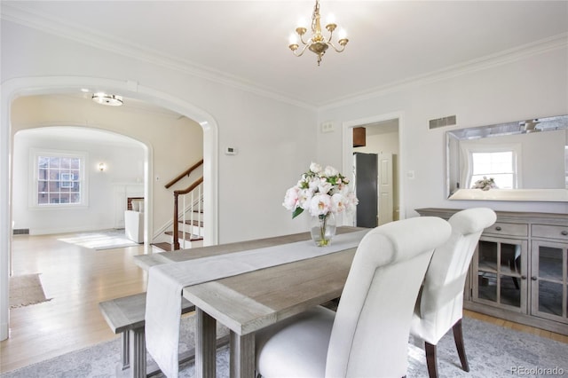 dining area with crown molding, a notable chandelier, and light wood-type flooring