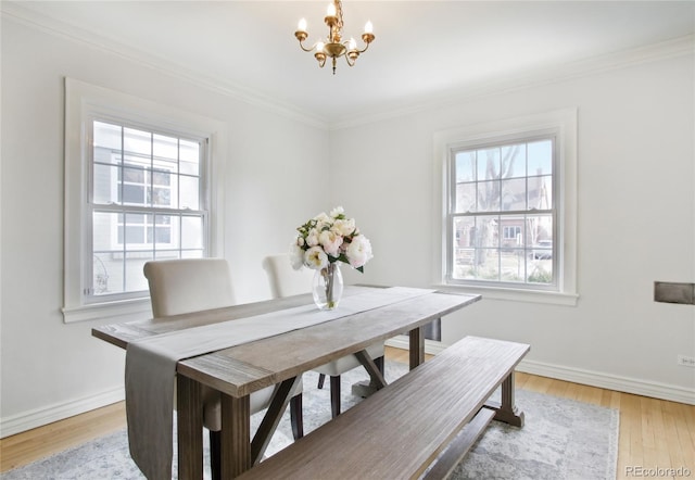 dining space with a notable chandelier, ornamental molding, and light wood-type flooring