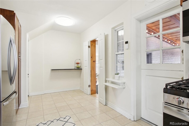 kitchen featuring stainless steel appliances, vaulted ceiling, and light tile patterned floors