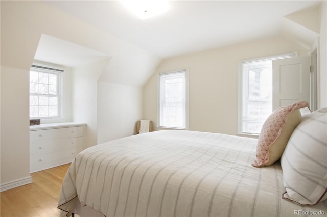 bedroom featuring lofted ceiling, light hardwood / wood-style floors, and multiple windows