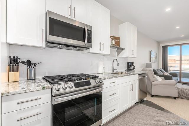 828 Grand Ave Unit 201C, Grand Lake, CO 80447 - kitchen with stainless steel appliances, open floor plan, white cabinetry, backsplash, and recessed lighting