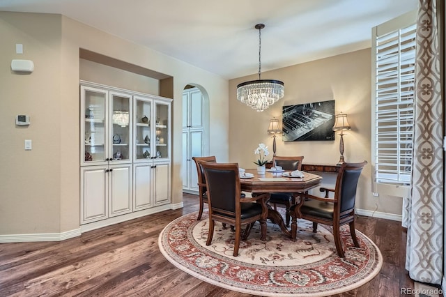 3181 Firenze Pl, Highlands Ranch, CO 80126 - dining area with a chandelier, arched walkways, dark wood-style flooring, and baseboards