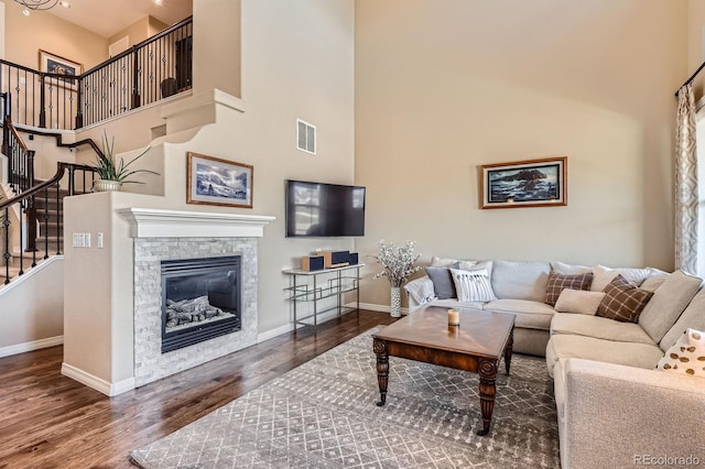 3181 Firenze Pl, Highlands Ranch, CO 80126 - living room with a towering ceiling, wood finished floors, stairs, and a stone fireplace
