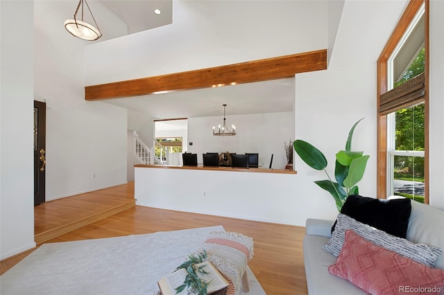 living room featuring light wood-type flooring, a towering ceiling, and beamed ceiling